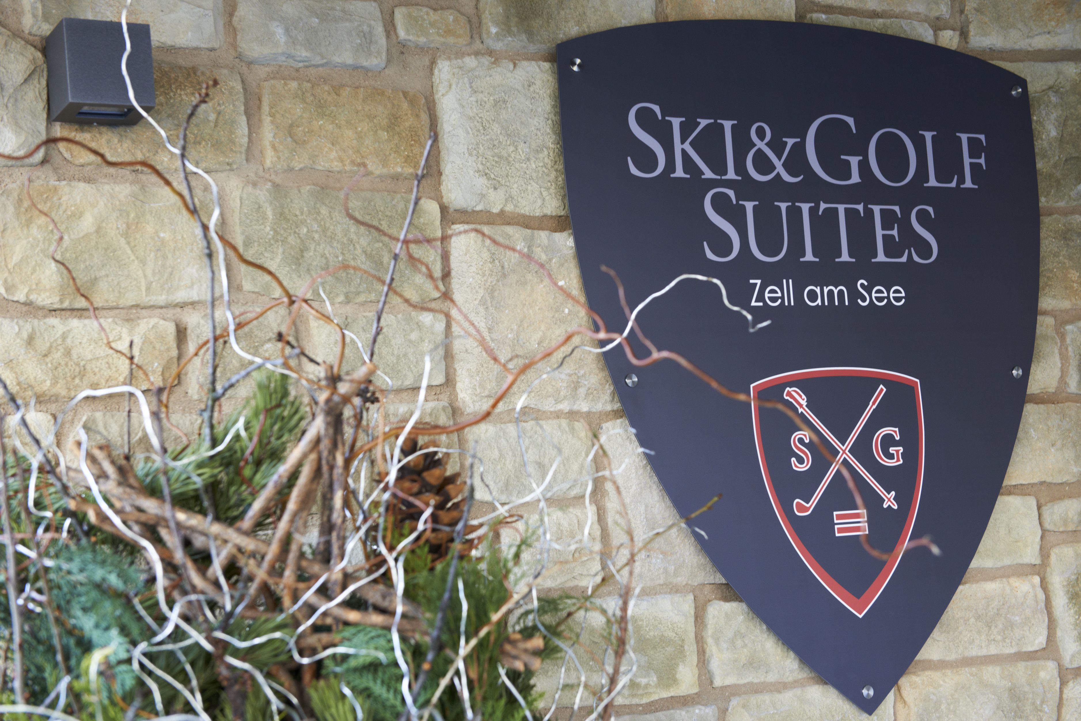 A sign for Ski & Golf Suites with a logo and the tagline "Zell am See".
