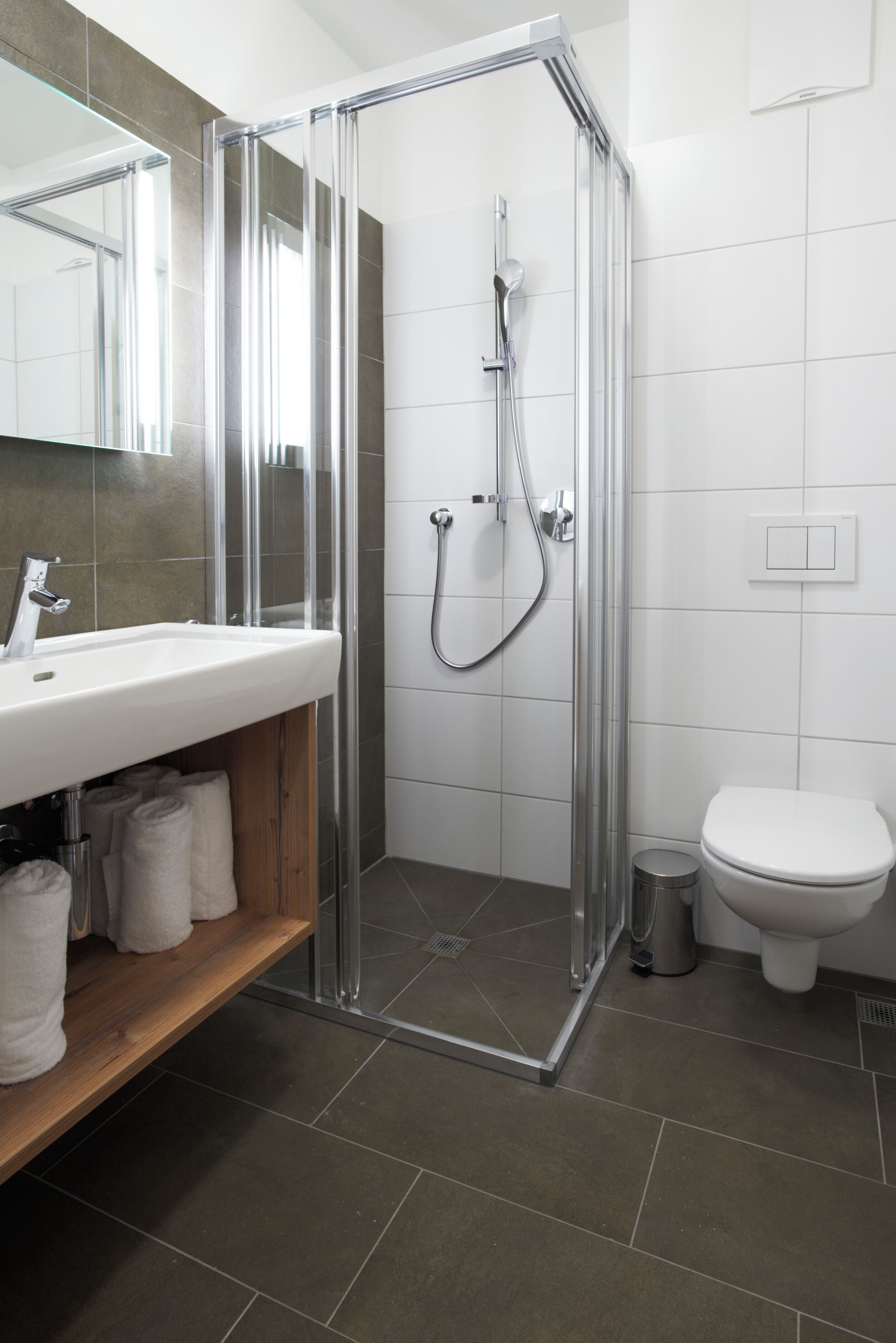 Un baño moderno con ducha acristalada, lavabo blanco y un inodoro.