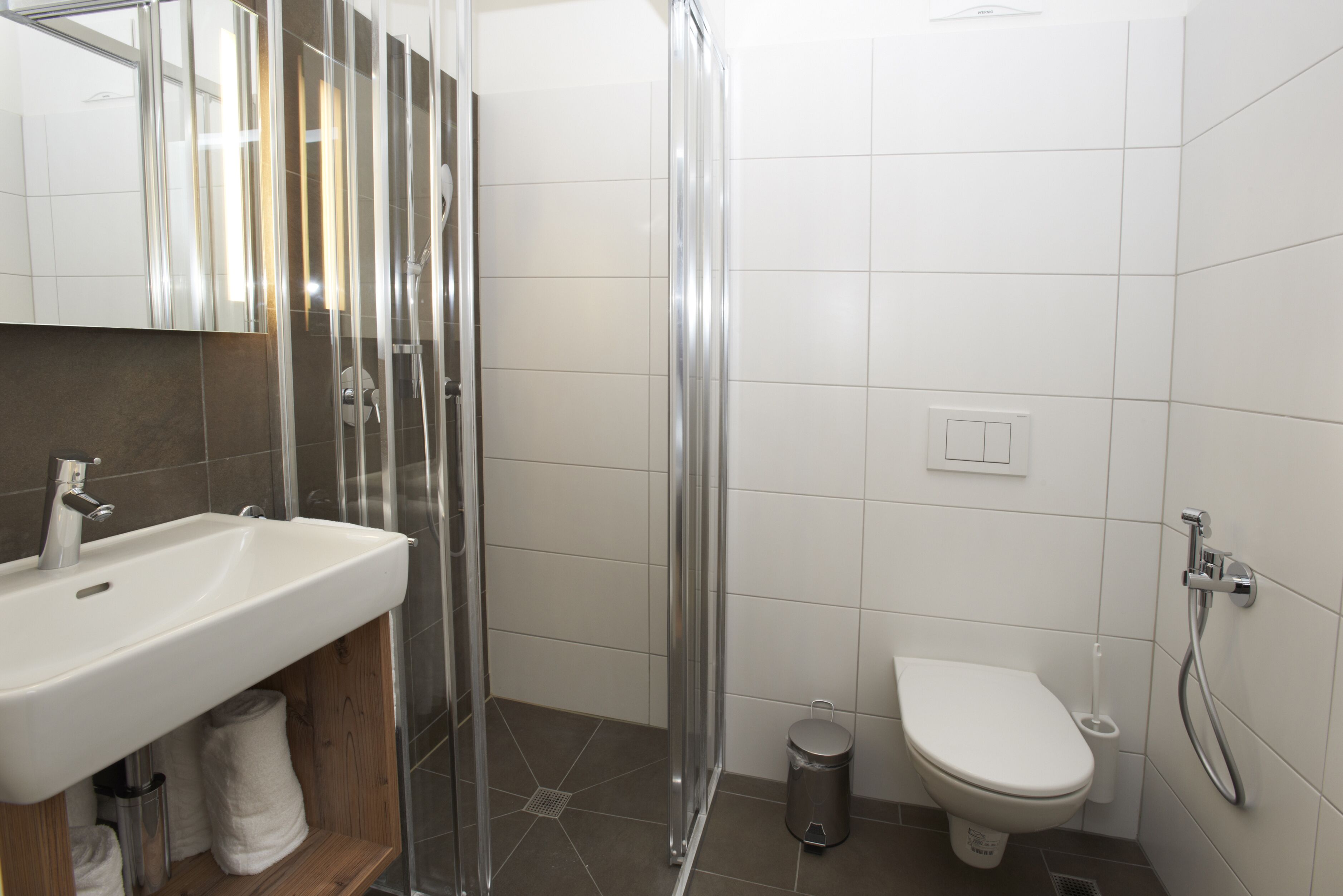 Un baño moderno con cabina de ducha de vidrio, un lavamanos blanco y un inodoro.
