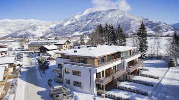 Un edificio moderno de dos pisos con balcón, rodeado por un paisaje nevado y montañas.