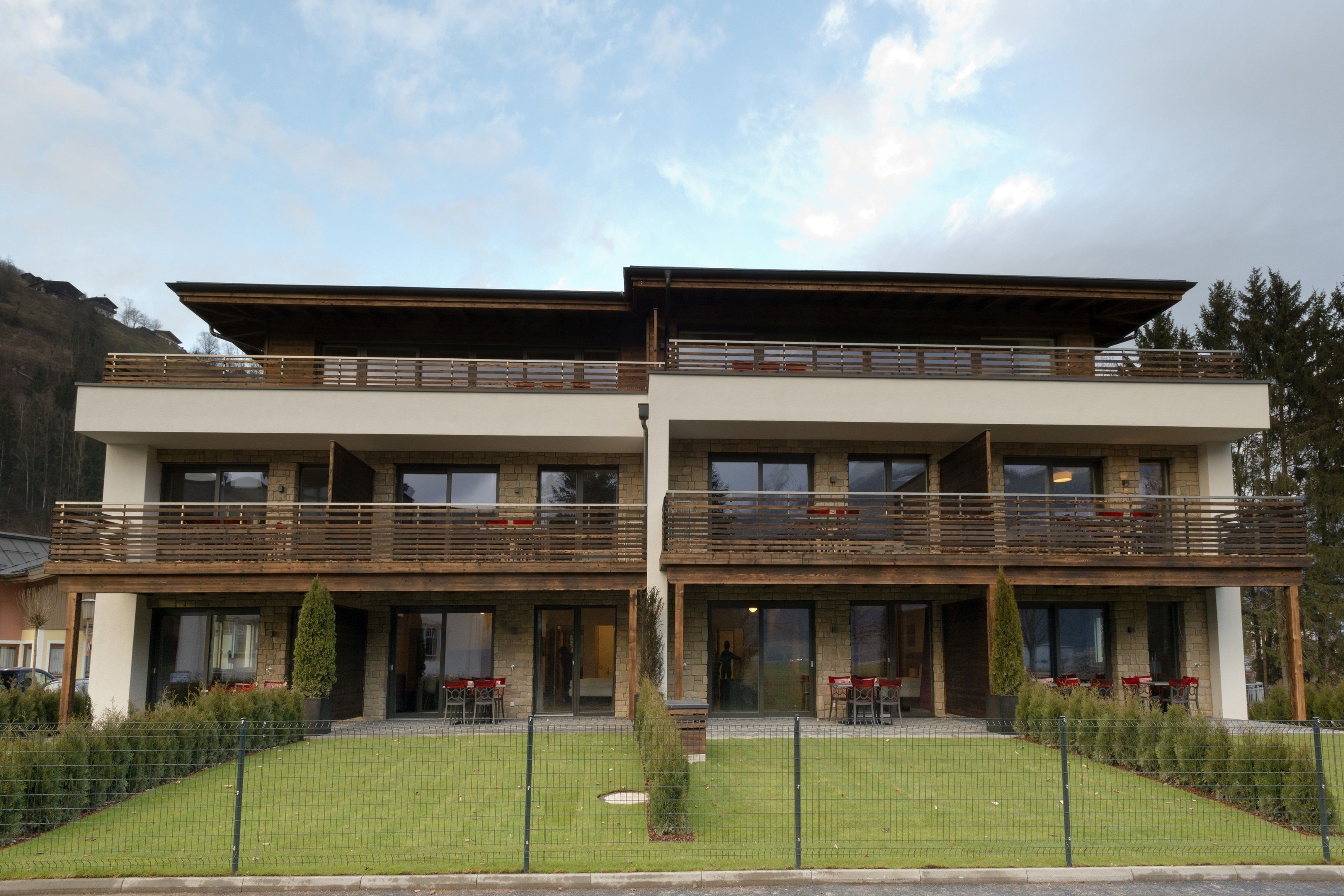 A two-story building with a flat roof, balconies, and a fenced front yard.