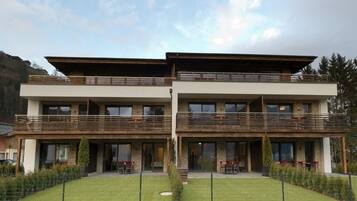 A two-story building with a flat roof, balconies, and a fenced front yard.