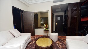 A modern hotel lobby with a white sofa, a round wooden coffee table, and a small side table with a vase of flowers. - Hôtel Fleur de Lys Plateau (Dakar)