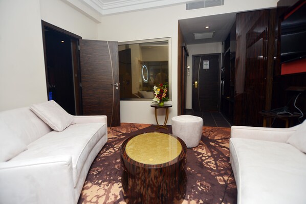 A modern hotel lobby with a white sofa, a round wooden coffee table, and a small side table with a vase of flowers.