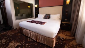 A hotel room with a large bed, a mirror, a nightstand, and a wall-mounted lamp. - Hôtel Fleur de Lys Plateau (Dakar)