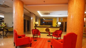 A lobby with red chairs, a reception desk, and a large pillar. - Hôtel Fleur de Lys Plateau (Dakar)