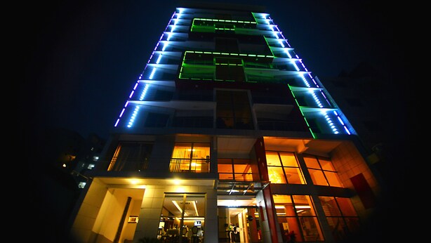 A multi-story building with illuminated exterior lighting and a visible entrance with steps leading up to it. - Hôtel Fleur de Lys Plateau (Dakar)