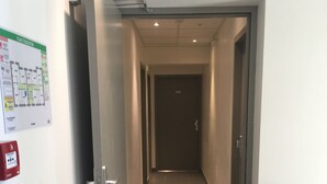 A corridor with a fire alarm and a floor plan on the wall. - Le Logis Dauphinois (Roussillon-en-Isere)