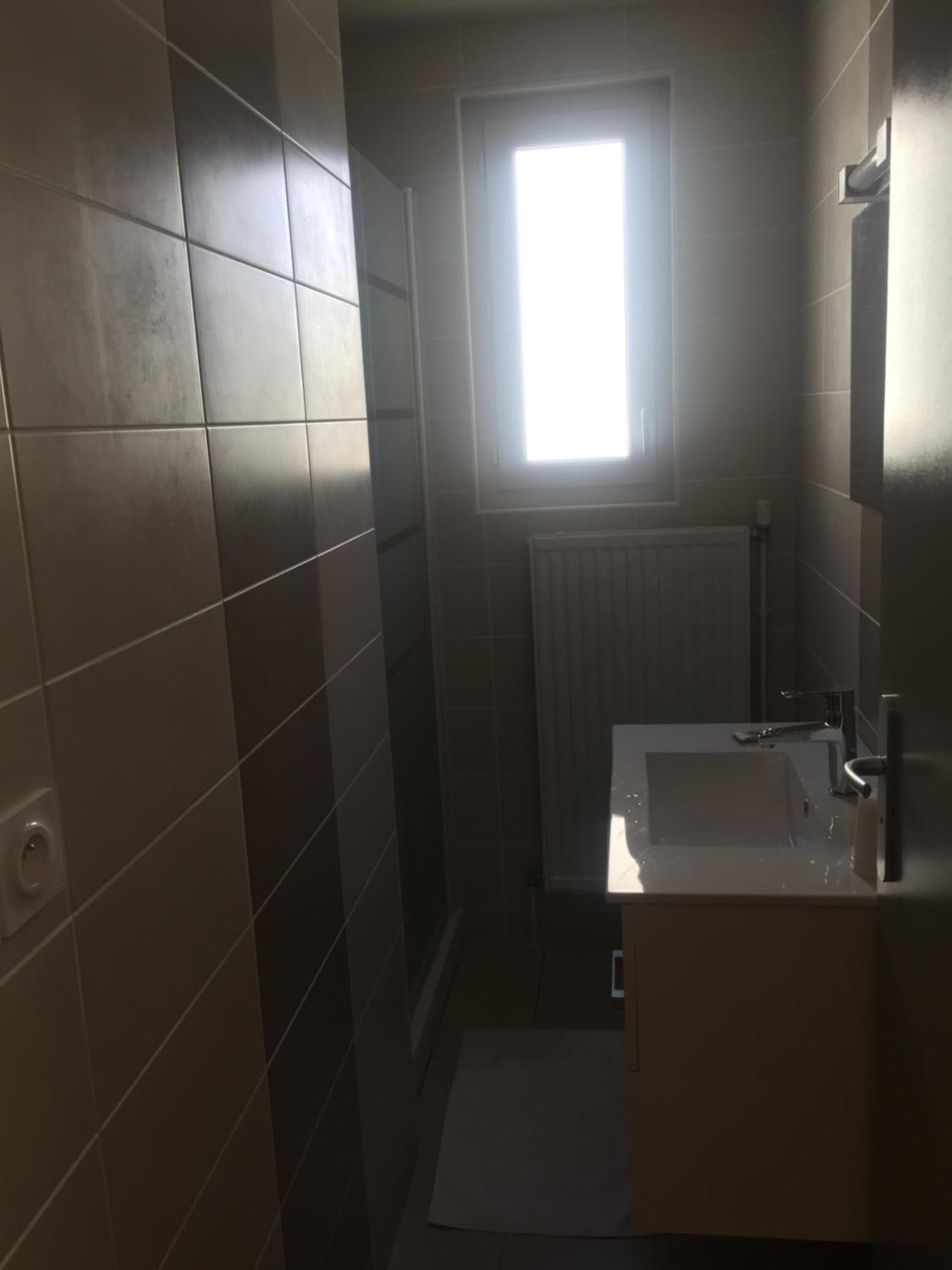 A bathroom with a window, a sink, and a mirror.