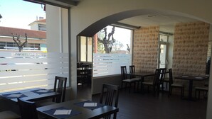 A restaurant with multiple tables and chairs, large windows, and a brick wall. - Le Logis Dauphinois (Roussillon-en-Isere)