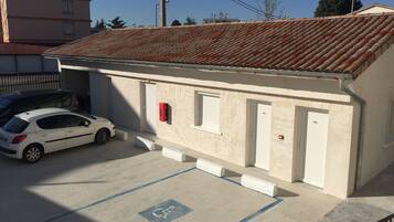 A building with a tiled roof, a white car parked in front, and a disabled parking space.