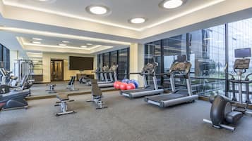 Un gimnasio moderno con cintas de correr, elípticas y pesas libres.
