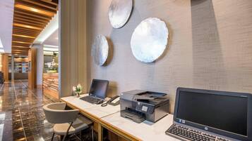 A reception desk with a laptop, a printer, and a desktop computer. There are three decorative wall pieces above the desk.