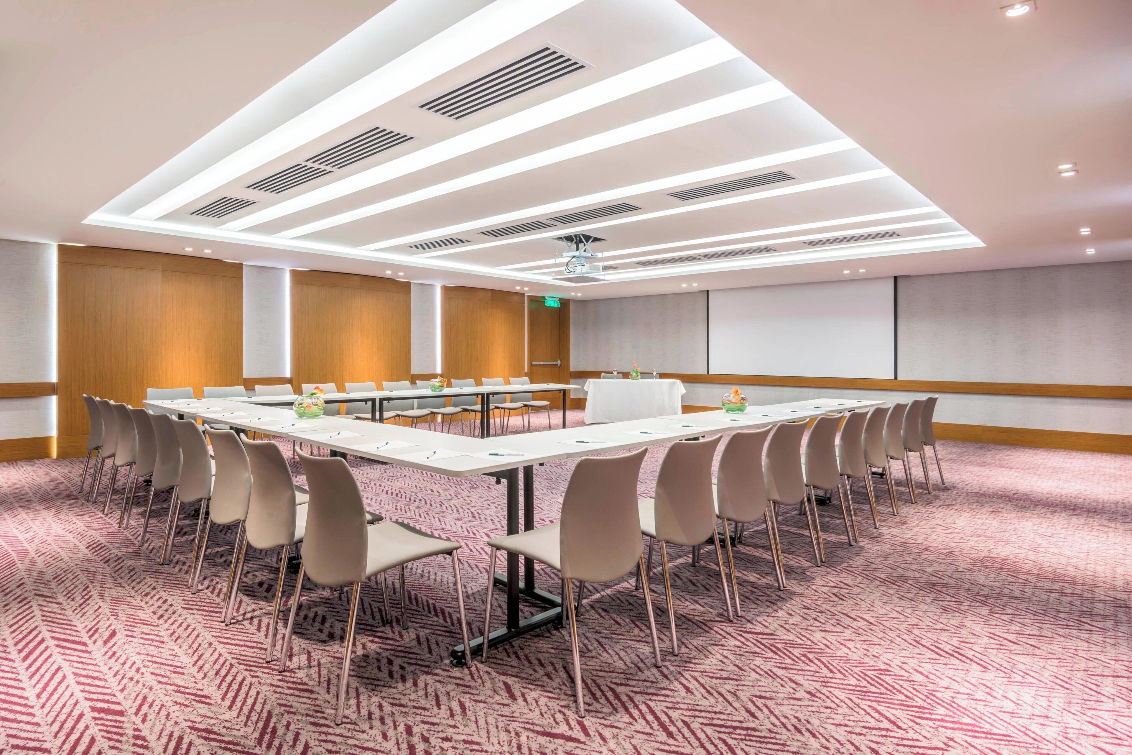 A conference room with a long table, multiple chairs, and a patterned carpet.