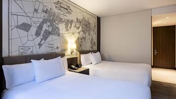 Ein Hotelzimmer mit zwei Betten, einer großen Karte an der Wand, einem Nachttisch mit Lampe und einer Holztür.