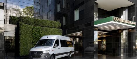 Entrada de un hotel Courtyard Marriott con una camioneta blanca estacionada frente.