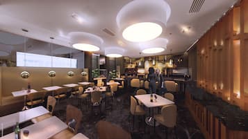 Un interior de restaurante moderno con mesas redondas, asientos de bar y una zona de bar con fondo de madera.