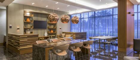 A modern kitchen with a marble island, built-in oven, and a flat-screen TV.