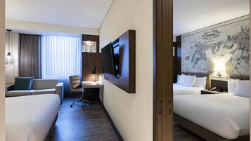 Een hotelkamer met twee bedden, een bureau, een televisie en een grote kaart aan de muur.