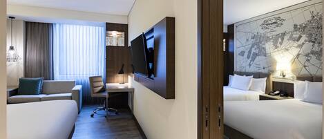 Habitación de hotel con dos camas, un escritorio, un televisor y un mapa grande en la pared.