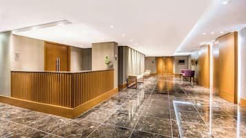 Un vestíbulo de hotel con mostrador de recepción, zona de estar y suelo de mármol.