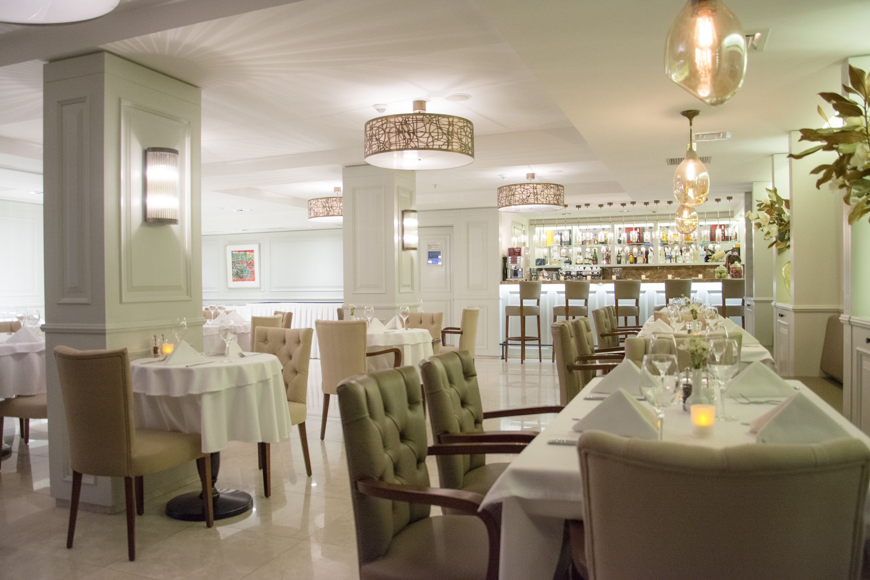 Ein Restaurant mit mehreren Tischen, Stühlen und hängenden Lampen.