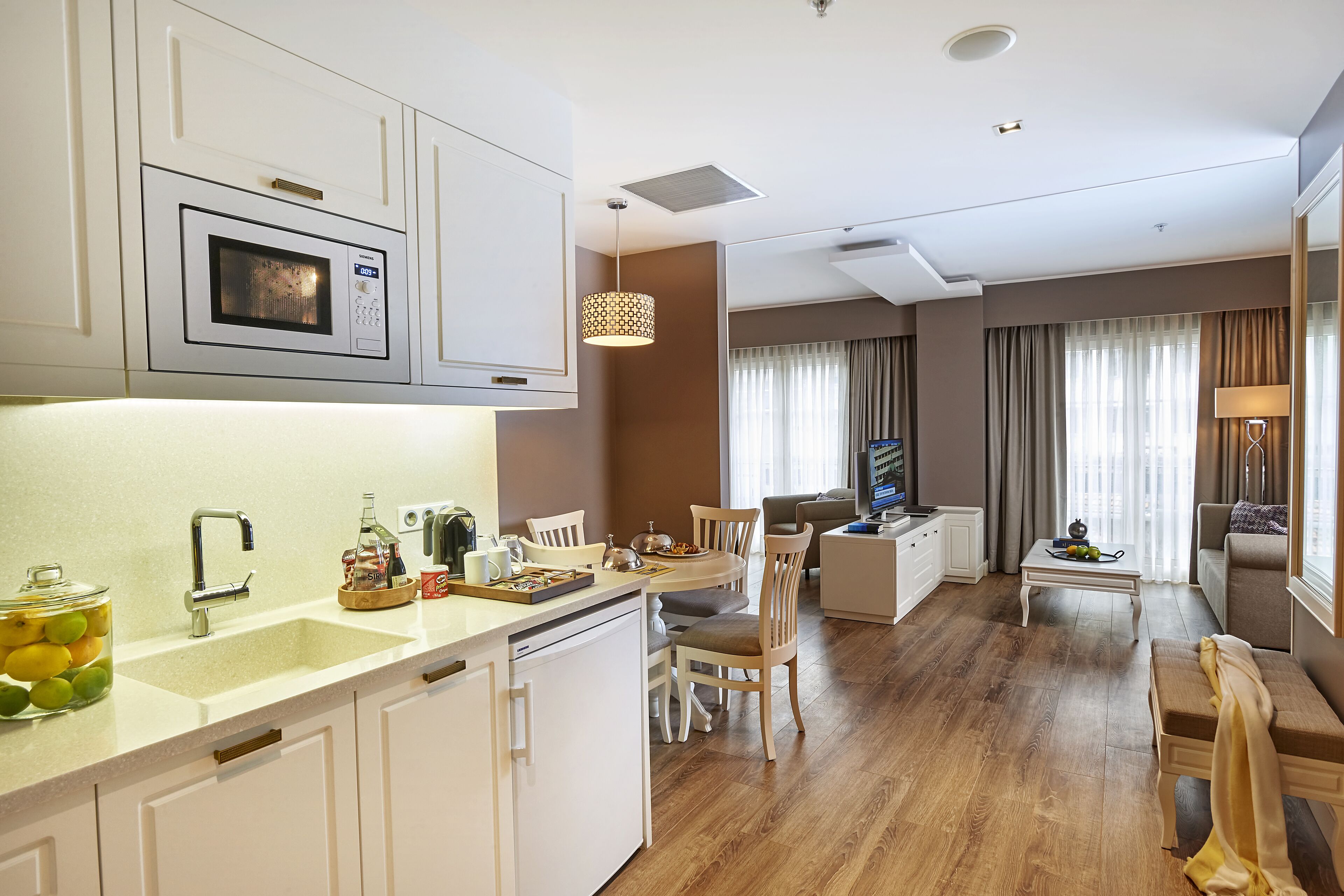 A modern kitchen with a built-in microwave, a sink, and a dining area with a table and chairs.