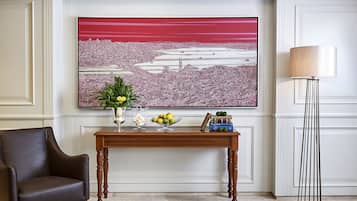 Une pièce décorée d’un grand tableau représentant un paysage urbain, d’une console en bois agrémentée d’objets décoratifs, d’un fauteuil en cuir marron et d’un grand lampadaire.