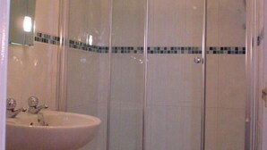 A bathroom with a glass shower enclosure, a sink, and a mirror. - The Old Courthouse (Windermere)