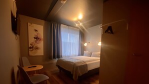 Une chambre d’hôtel avec un lit, une chaise, une table et un tableau au mur.