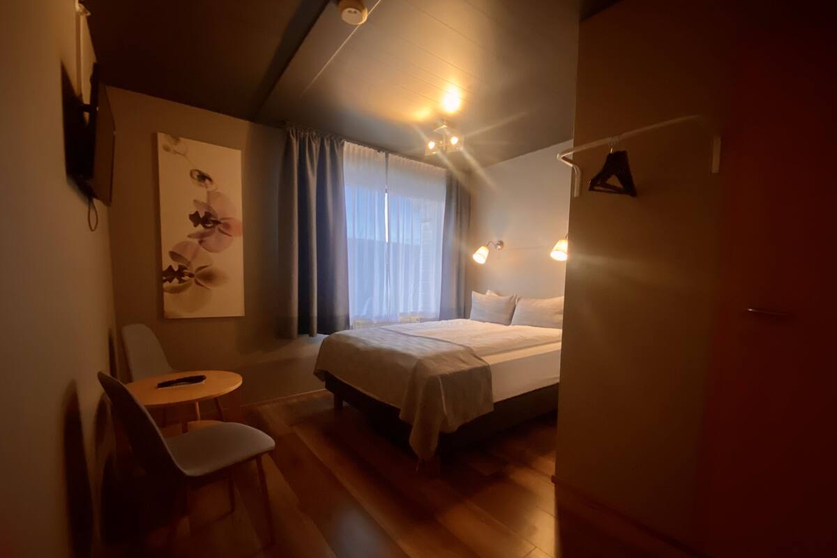 Een hotelkamer met een bed, een stoel, een tafel en een schilderij aan de muur.