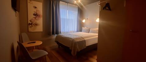 Une chambre d’hôtel avec un lit, une chaise, une table et un tableau au mur.