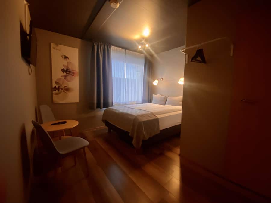 Une chambre d’hôtel avec un lit, une chaise, une table et un tableau au mur.