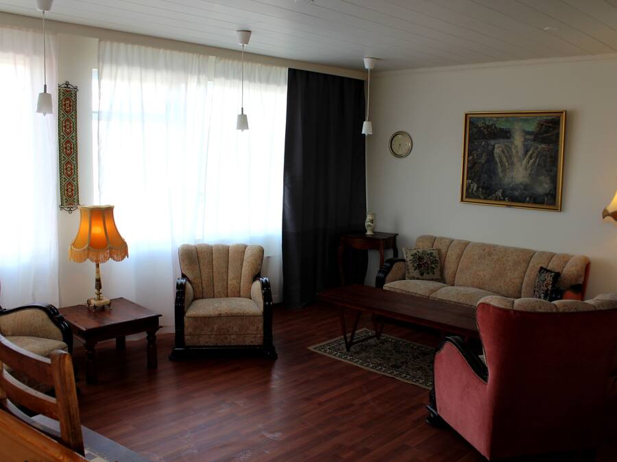 A living room with a sofa, armchairs, a coffee table, and two lamps.