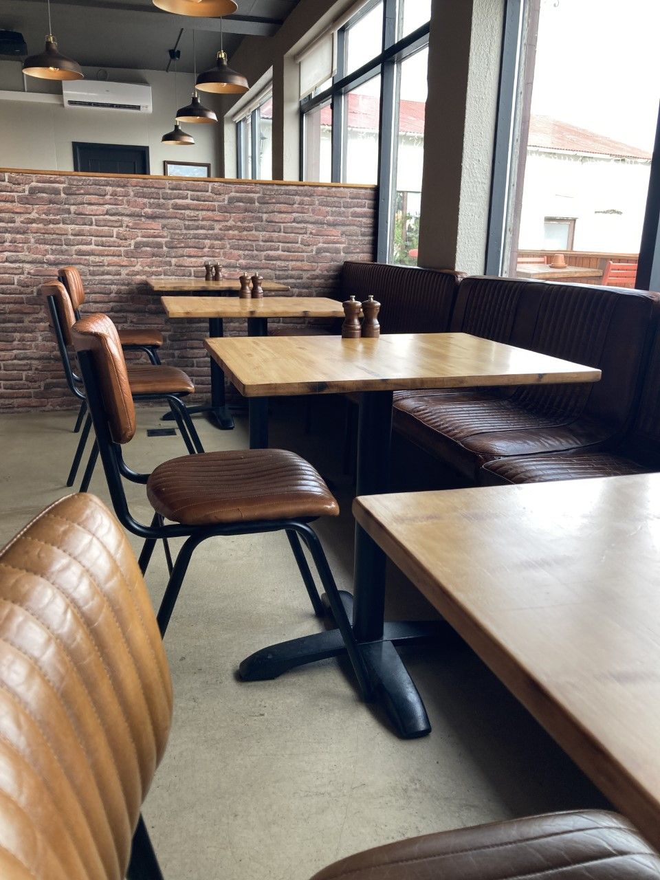 A restaurant interior with brick walls, wooden tables, and leather booths.