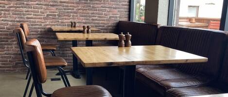 A restaurant interior with brick walls, wooden tables, and leather booths.