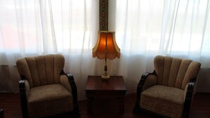 Une pièce comprenant deux fauteuils, une petite table en bois et une lampe.