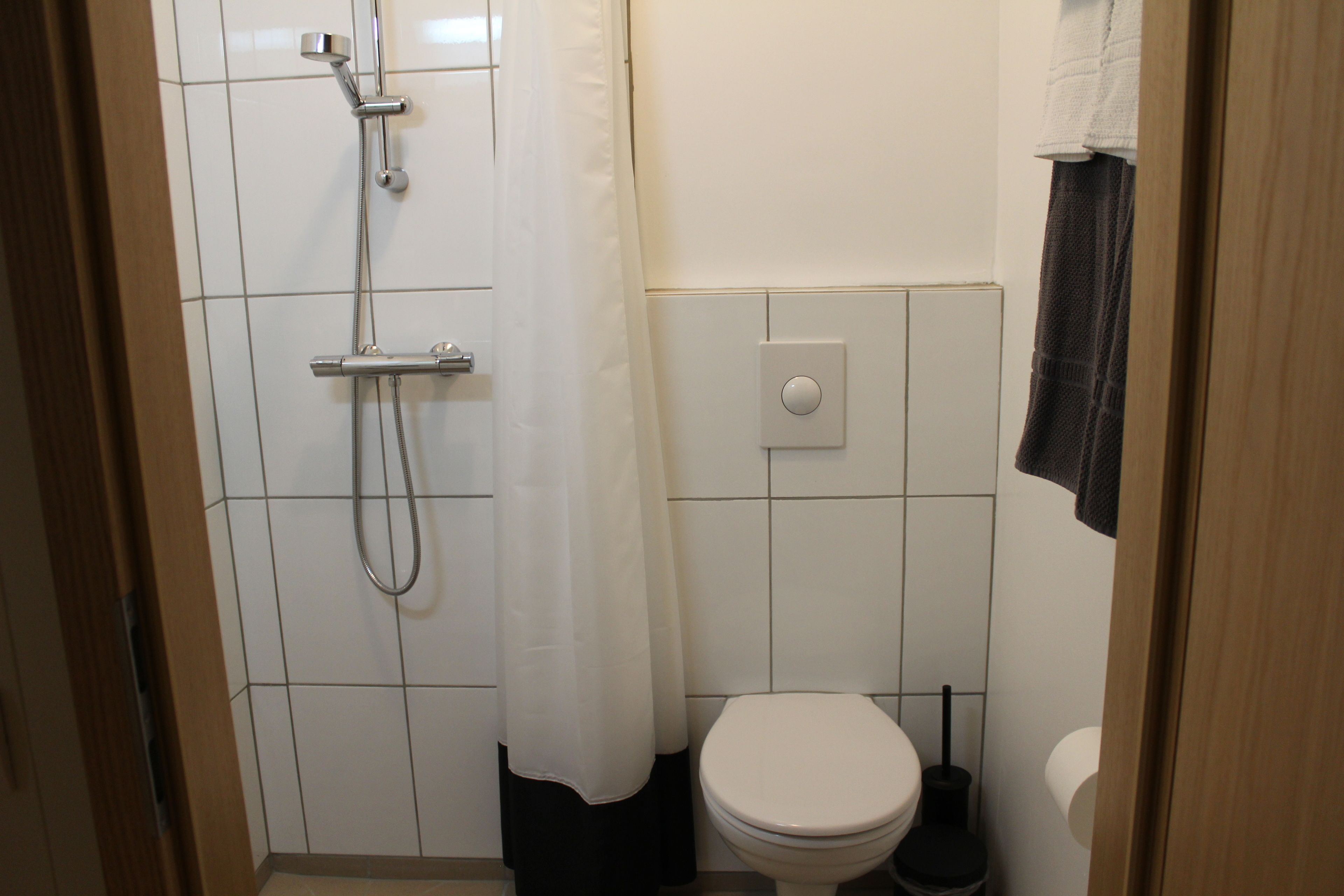 Ein kleines Badezimmer mit Dusche, Toilette und einem Handtuch an der Wand.