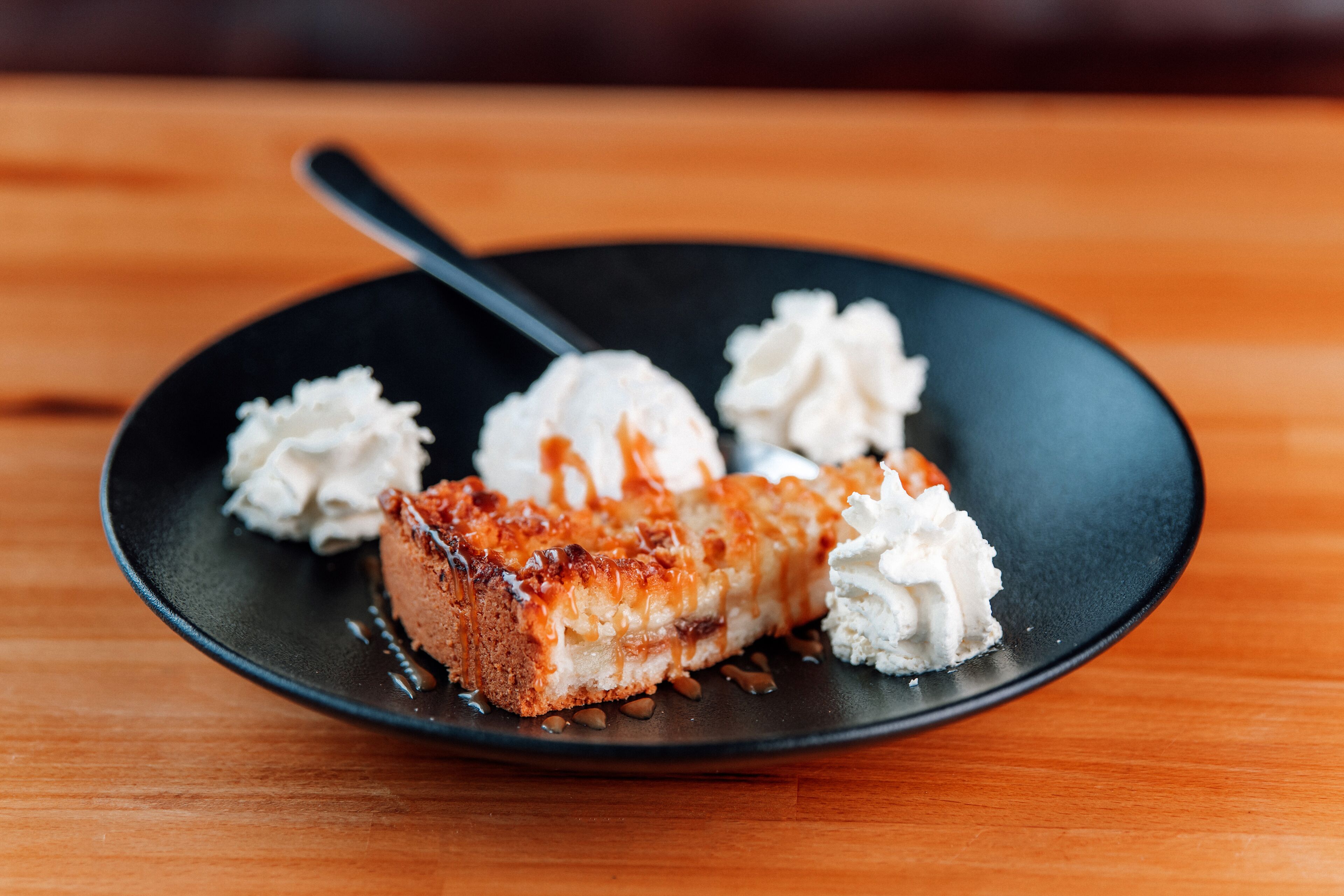 Une assiette à dessert avec une part de g âteau et de la crème fouettée, le tout présenté sur une assiette noire.
