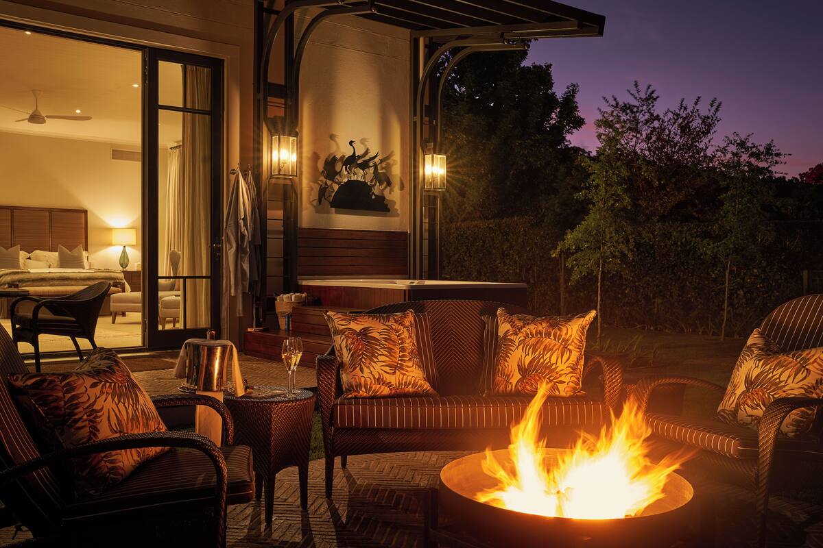 An outdoor patio with wicker furniture, a fire pit, and a view of the interior.