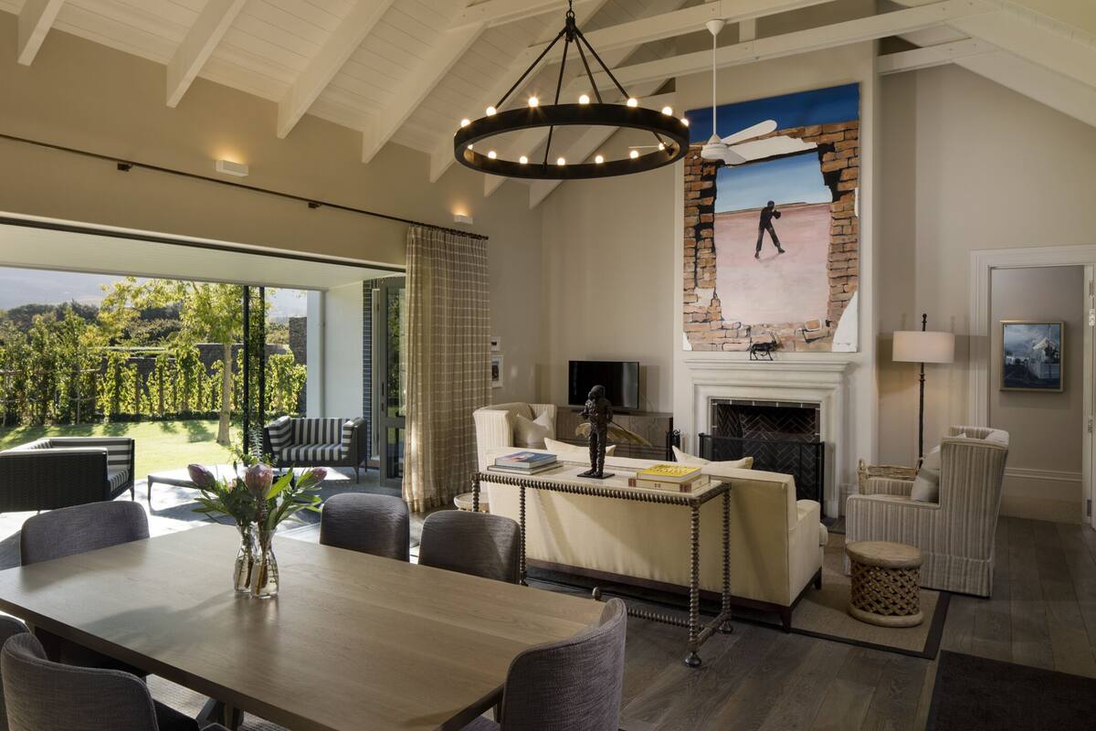 A spacious living room with a fireplace, a dining area with a table and chairs, and a large window overlooking a garden.