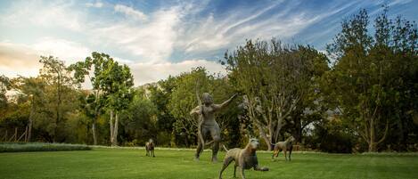 Un parque con césped, árboles y una estatua.