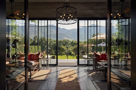 A spacious room with large windows, a chandelier, and a view of mountains.