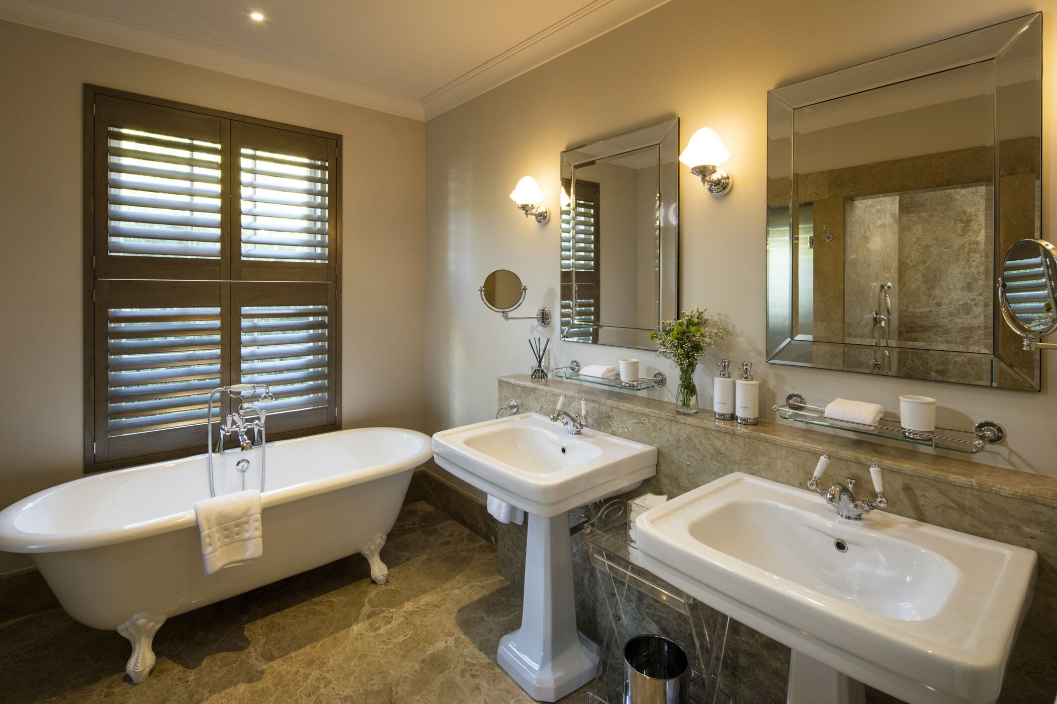 A bathroom with a freestanding bathtub, two sinks, and a large mirror.