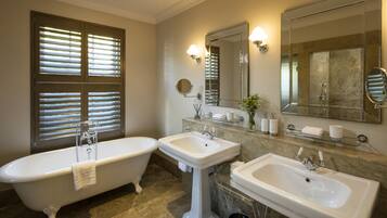 A bathroom with a freestanding bathtub, two sinks, and a large mirror.
