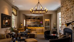 Een gezellige zithoek met een bar, comfortabele stoelen, een open haard en een grote kroonluchter.