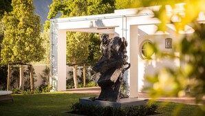 Een sculptuur in een tuin, met een wit gebouw op de achtergrond.