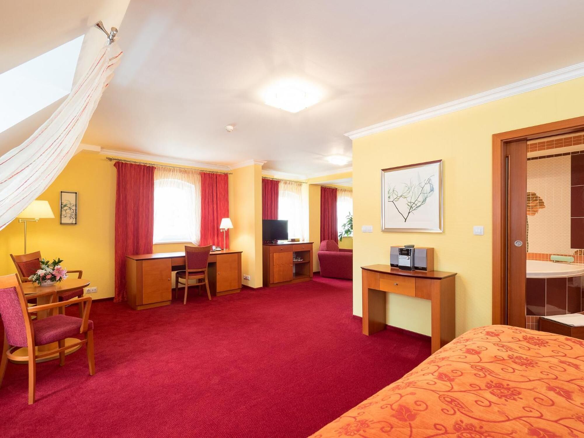 A hotel room with a bed, desk, chair, and a television.