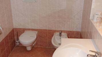 Ein Badezimmer mit Toilette, Bidet, Waschbecken und Mülleimer.