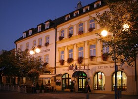 Un hotel de estilo arquitectónico europeo clásico, con ventanas arqueadas y un letrero que dice "HOTEL KORUNA RESTAURANT".